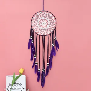 Bellissimo acchiappasogni viola da parete con pizzo bianco e piume per la decorazione.