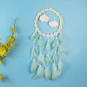 Detail van een handgemaakte madeliefje dromenvanger met muntgroene veren en wolken