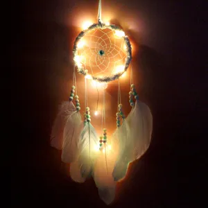 Vue détaillée d'un attrape-rêves artisanal avec des guirlandes LED chaudes et des plumes