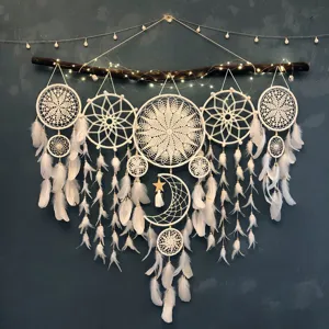 Handmade white crochet dream catcher with feathers and fairy lights for home wall decor.