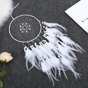 Détail d'attrape-rêves blanc, avec plumes délicates, perles blanches et filet tissé.
