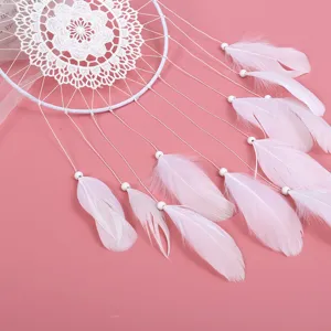 Traumfänger Detailaufnahme mit weißem Spitzennetz und rosa Federn. Ideale Raumdekoration.