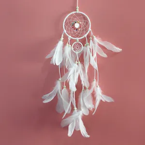 Detalle de atrapasueños blanco hecho a mano con plumas delicadas y cuentas de madera.