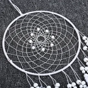 Gros plan détail du décor suspendu attrape-rêves blanc avec filet tissé complexe et perles blanches.