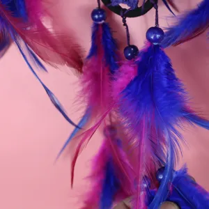 Detailed closeup of handmade dream catcher feathers and beads, vibrant blue and pink decor.