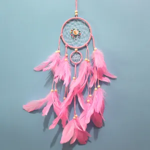 Vista detallada del atrapasueños rosa hecho a mano con plumas y cuentas para decoración.