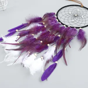 Handmade dreamcatcher with white and purple feathers, turquoise beads, and black ring for wall decor.