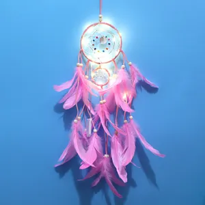 Vista detallada del atrapasueños rosa hecho a mano con luces LED y plumas suaves.