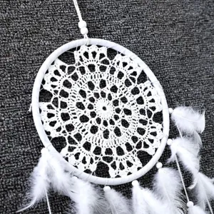 Detail van witte gehaakte dromenvanger met veren en kraaltjes voor huis- en bruiloftsdecor.