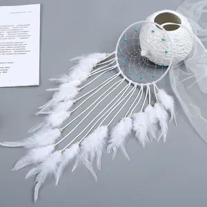 Detailweergave van witte handgeweven dromenvanger met veren en blauwe kralen