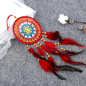 Vue détaillée d'un attrape-rêves rouge fait main avec plumes et perles colorées