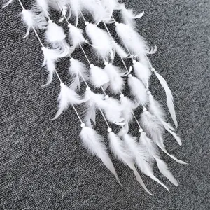 Witte dromenvanger hanger detailweergave, close-up van zachte veren en kleine kraaltjes.