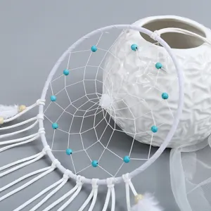 Detailopname van een handgeweven witte dromenvanger met blauwe kralen en net