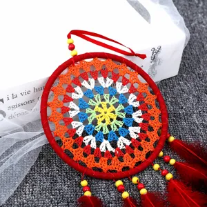 Gros plan d'un attrape-rêves rouge fait main avec toile au crochet colorée et plumes.