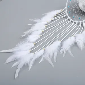 Detail van een witte handgemaakte dromenvanger met zachte veren en turquoise kralen.