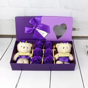 Détail d'un coffret cadeau violet avec deux ours en peluche et six roses de savon violet.