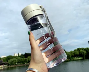 Vue détaillée de la gourde en plastique transparent avec graduations et dragonne pratique.