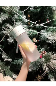 Nahaufnahme des tragbaren, mattierten Plastikwasserbechers vor weihnachtlicher Baumdekoration.