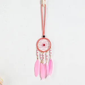 Close-up detail of pink dreamcatcher necklace with feathers and beads on white wall