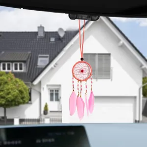 Pink dreamcatcher car ornament with delicate feathers and beads hanging from a mirror