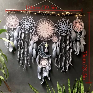 Detailed view of the handmade gray dream catcher wall hanging with delicate feathers and stars.
