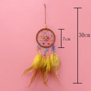 Detalle del atrapasueños con anillo tejido, cuentas de colores y plumas amarillas.