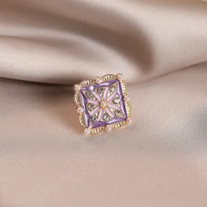 Elegant close-up of a vintage purple enamel brooch featuring pearls and crystals.