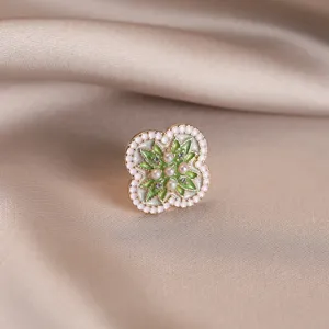 Detailed macro view of an elegant green enamel flower brooch with pearl accents on satin