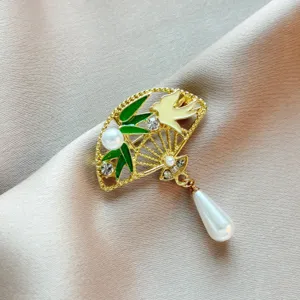 Elegante κομψή χρυσή καρφίτσα βεντάλιας με πράσινο μπαμπού, πουλί, στραζ και μαργαριτάρι.