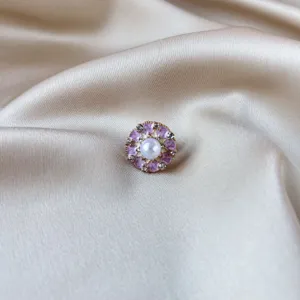 Close-up of a vintage Chinese style purple enamel flower brooch with a pearl center on silk