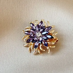 Elegant flower brooch featuring marquise-cut purple crystals and gold plated metal petals