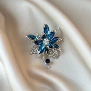 Detailed macro view of an elegant floral silver brooch with sparkling blue crystals.