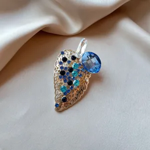 Detailed view of a luxury insect brooch with blue crystals on champagne satin background.