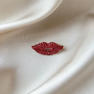 Vue detaillee de la broche levres en strass rouges, elegante epingle brillante pour costumes de femme.