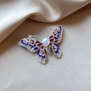 Elegant butterfly brooch featuring a large center pearl and purple enamel wings