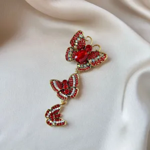 Close-up macro detail of a vintage triple butterfly brooch with red rhinestones on silk