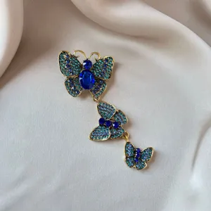 Detailed view of a vintage three-butterfly brooch with blue and teal rhinestones.
