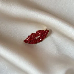 Gros plan détaillé d'une broche lèvre en strass rouge sur fond de tissu en soie.