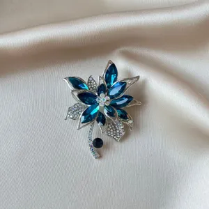 Close-up detail of the elegant blue crystal flower brooch with silver tone and sparkling rhinestones.