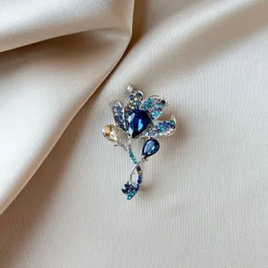 Close-up of an elegant floral crystal brooch with deep blue rhinestones on silk fabric