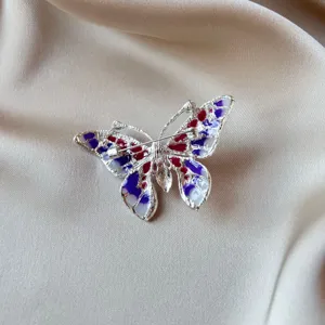 Detailed view of a vintage butterfly brooch with vibrant purple and red enamel details