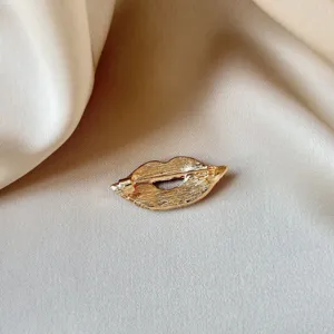 Vue détaillée de broche lèvre dorée, épingle en métal élégante pour accessoires de mode.