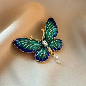 Detailed close-up of elegant green enamel butterfly brooch with crystal pendant