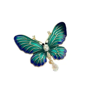 Elegant butterfly brooch with vibrant blue-green enamel wings and crystal teardrop pendant