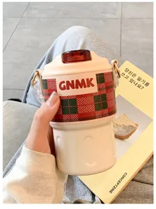 Detailed view of portable stainless steel insulated coffee cup with red and green plaid sleeve