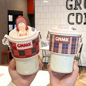 Close-up of two INS style 316 stainless steel thermal coffee cups with plaid sleeves.
