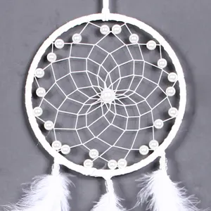 Close-up details van de zuiver witte handgemaakte dromenvanger met delicate veren en parels.