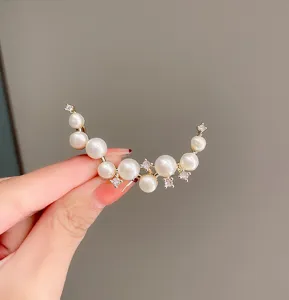 Close-up of elegant crescent pearl brooch with sparkling zirconia, delicate suit accessory.
