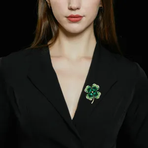 Detailed shot of a vintage green crystal four leaf clover brooch pinned on black blazer.
