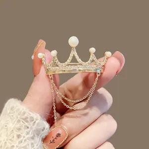 Exquisite gold crown brooch featuring sparkling rhinestones, faux pearls, and delicate hanging chains.